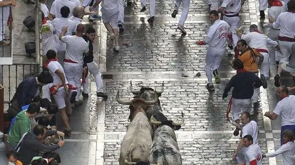 Mozos corren delante de los toros de Torrestrella durante uno de los encierros de San Fermín 2014.