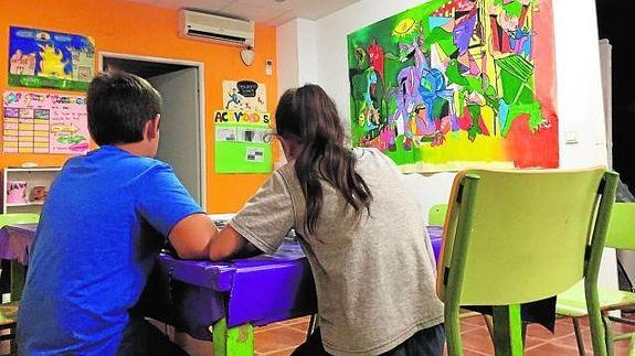 Dos niños usuarios de 'El Arca' pintan en su sede en Nazaret.