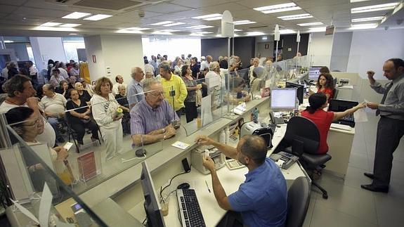 Varios pensionistas, que no tienen tarjeta de crédito o débito, hacen cola ante los mostradores de una sucursal bancaria 