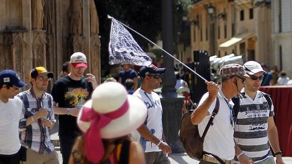 Un grupo de visitantes sigue a un guía turístico en la plaza de la Virgen de Valencia.