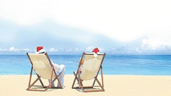 Gente en la playa con gorros de navidad.