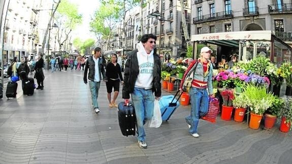 Turistas pasan ante un puesto de flores en Las Ramblas de Barcelona.