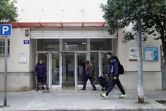 Dos pacientes en la entrada de un centro de salud de Valencia mientras un viandante pasa por la puerta. :: irene marsilla