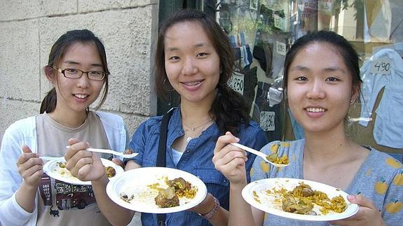 Tres turistas chinas degustan un plato de paellaLP