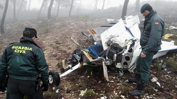 Miembros de la Guardia Civil junto a los restros de la avioneta siniestrada.