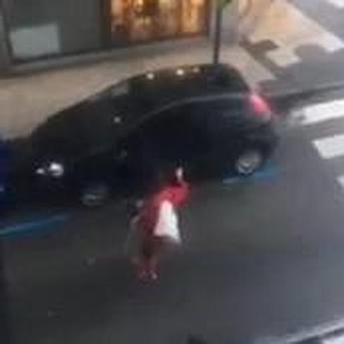 Una mujer intenta cerrar la puerta de su coche.