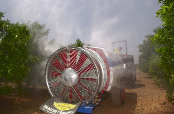 Un agricultor realiza un tratamiento contra plagas con  un turboatomizadore en una plantación de cítricos. :: J. peiró