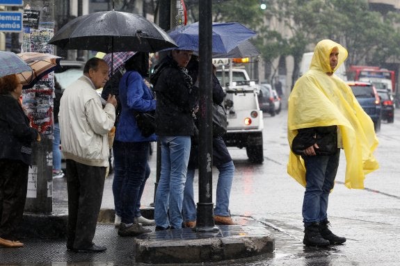 Varias personas se protegen de la lluvia, ayer, en Valencia. :: I.MARSILLA