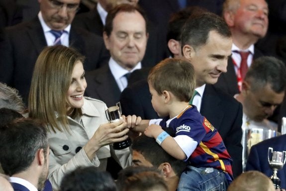 La Reina Letizia le entrega la reproducción de la copa a Benjamín, subido a los hombros de su padre, Luis Suárez. :: javier lizón/efe