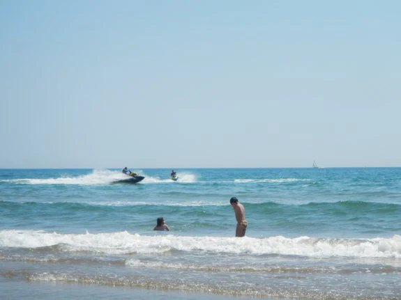 Dos menores se bañan a escasos metros de varias motos de agua, en una zona de la playa de La Patacona. :: lp