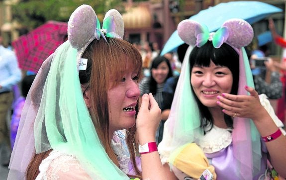 Dos amigas chinas esperan emocionadas a que se abra el parque de atracciones. :: afp