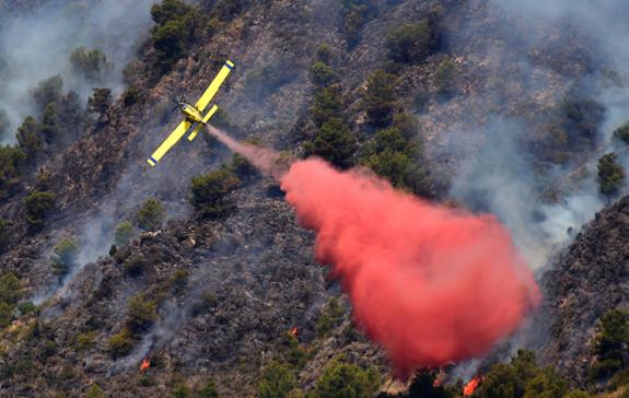 Una avioneta apaga el fuego en el monte.