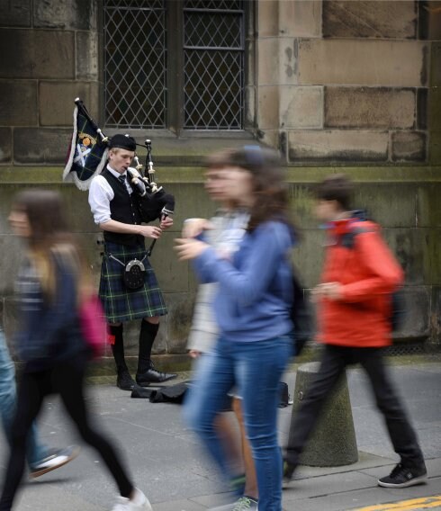 Un joven ataviado al estilo tradicional toca la gaita en una calle de Edimburgo.  A la derecha, dos escenas cotidianas en la capital escocesa y una manifestación independentista en Glasgow. 