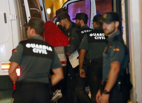 El presunto homicida con el rostro tapado con una sudadera roja, ayer, entra en el furgón de la Guardia Civil. :: jesús signes