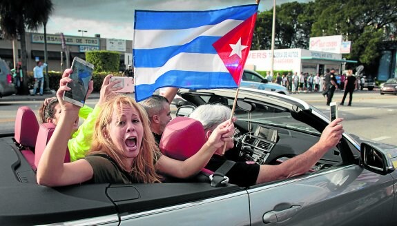 Jóvenes exhiben una bandera de Cuba mientras circulan en coche por Little Havana. :: reuters