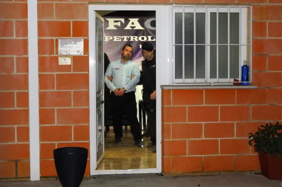 Uno de los detenidos sale con las manos esposadas de la empresa registrada por la Guardia Civil en Paterna. :: manuel molines
