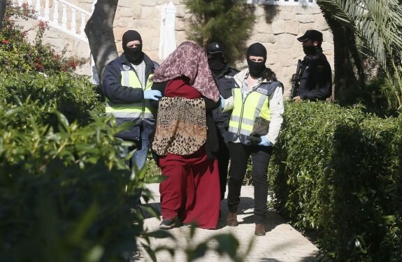 Dolores Hidalgo, con su rostro cubierto, acompañada por policías nacionales tras su arresto. :: efe