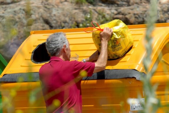 Un hombre deposita una bolsa de residuos en el contenedor amarillo. :: lp