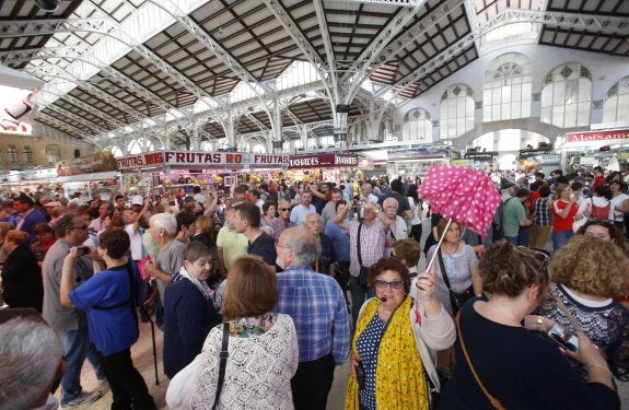 Una guía conduce a un grupo de turistas entre el gentío, este sábado en el Mercado Central. :: j. j. monzó