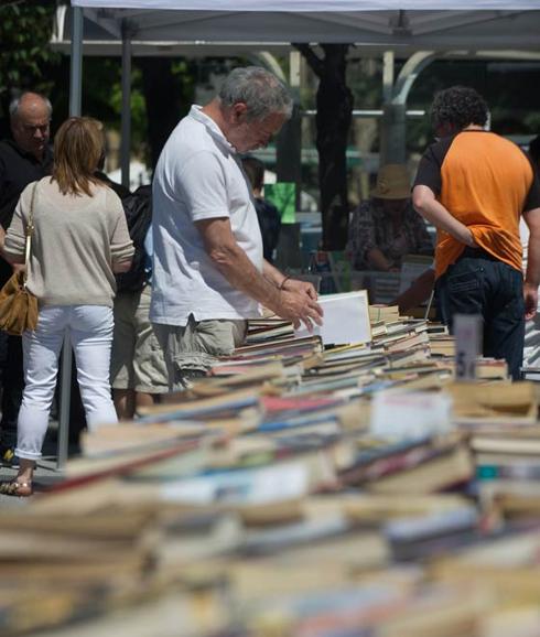 Un hombre ojea un libro en un mercado solidario.