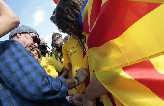 Lluís Llach, diputado de Junts pel Sí en el Parlament catalán, firma autógrafos durante la Diada de 2013. Abajo, en un concierto en los años 70. :: JOSé JORDAN / afp