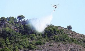Un helicóptero lanza agua en la zona del incendio. / Tino Calvo