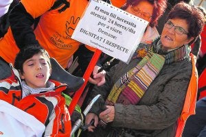 Una mujer empuja el carro de un niño con un cartel reivindicativo. / Juanjo Monzó