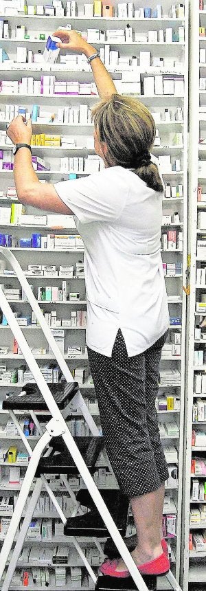Una farmacéutica guarda medicinas en su establecimiento. ::                             D. M.
