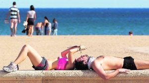 Dos personas toman el sol en una playa valenciana durante el día de ayer. ::                             DAMIÁN TORRES