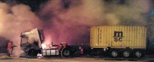 EXTINCIÓN DEL INCENDIO. Dos bomberos terminan de sofocar el incendio en una de las cabezas tractoras. /R. GIMÉNEZ