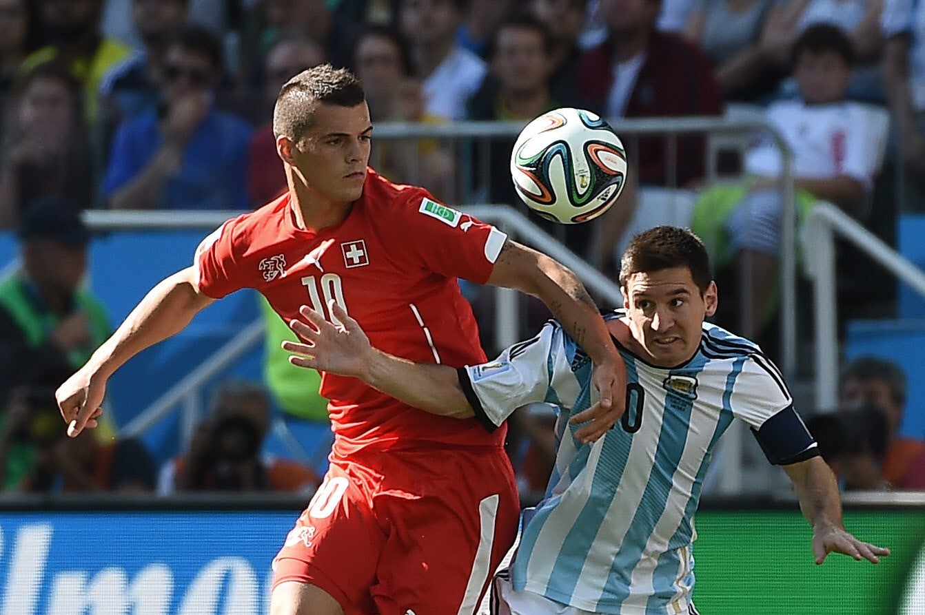 Leo Messi (d) pelea un balón con Granit Xhaka.