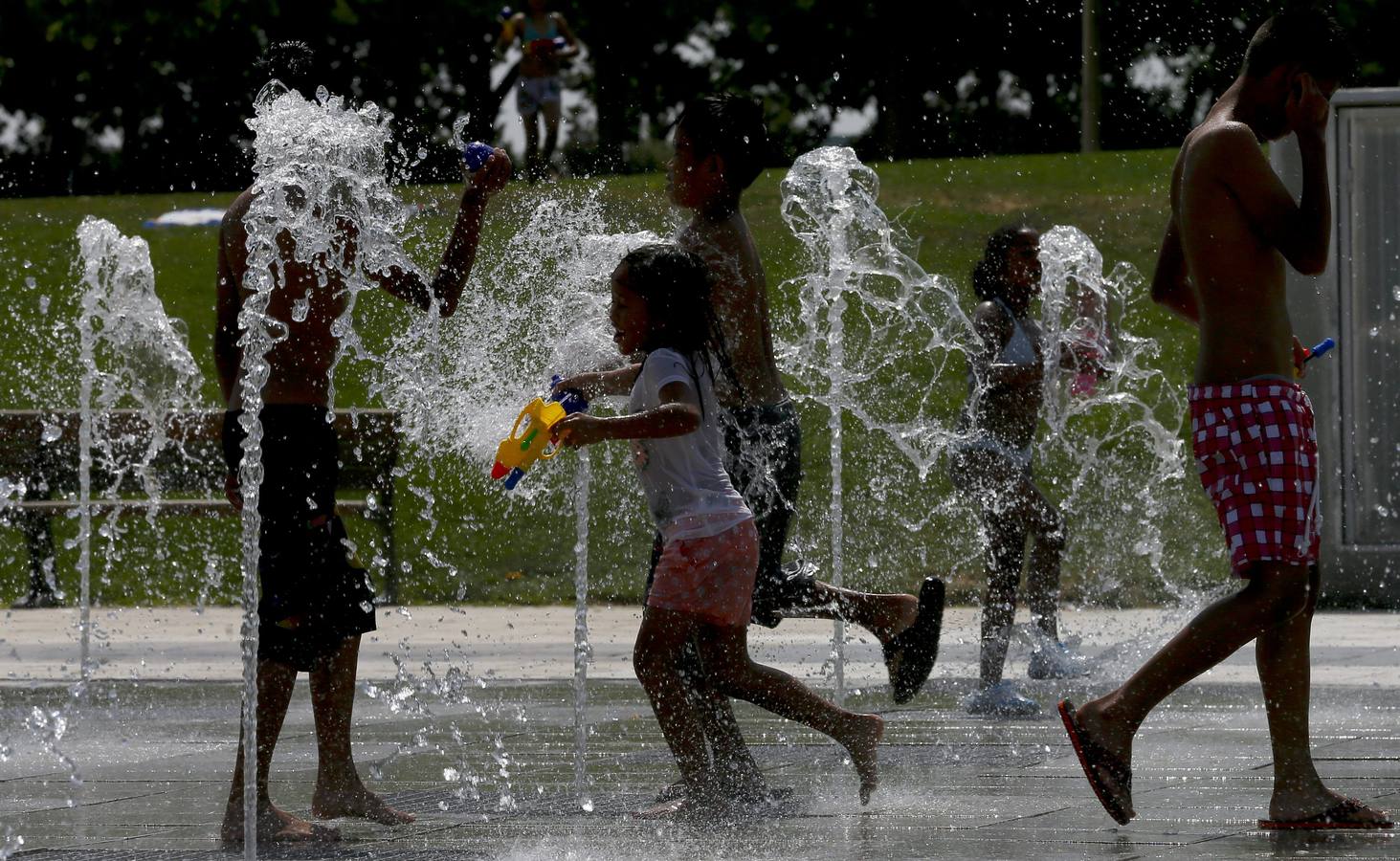 Niños jugando y refrescándose en una de las fuentes del parque Juan Carlos I en Madrid.