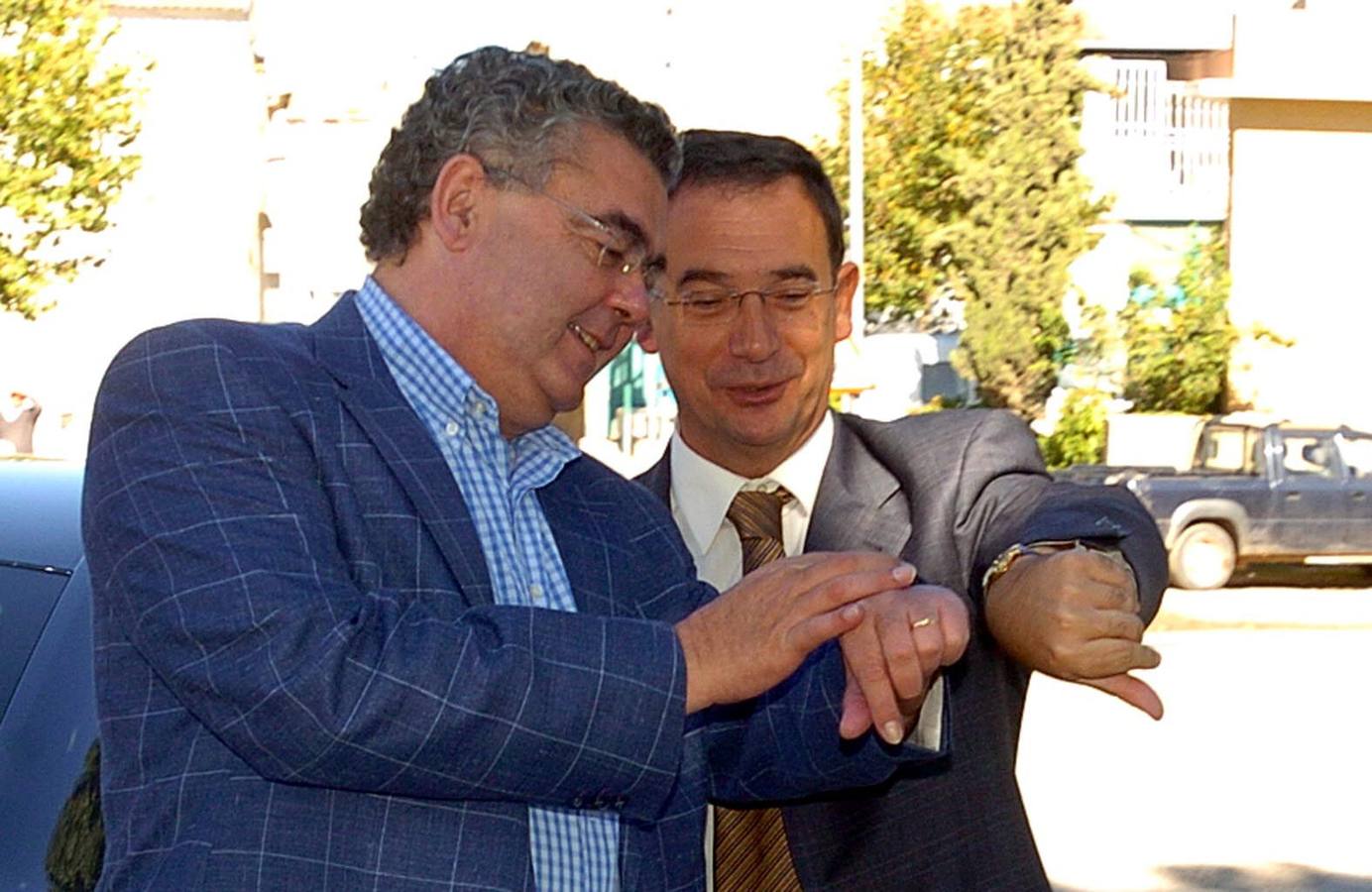 Miguel Navarro y Joaquín Bascuñana ajustan sus relojes mientras ponen la primera piedra de las obras de reparación y mejora de las carreteras C12 y C13. (10/2005)