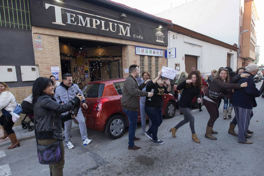 La vendedora de un cuarto premio de la Lotería Navidad, el número 59.444, Cristina Canovas (c), junto a su suegra, dueña del café el Templo, Josefina Moreno (3d), celebran la venta del número acompañados de vecinos, hoy en Rincón de Seca, Murcia.