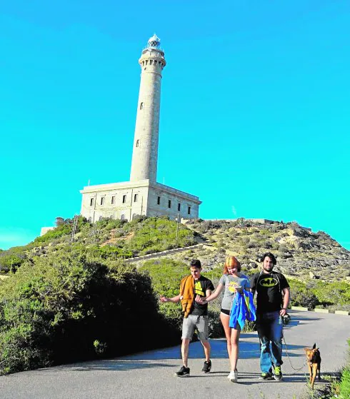 Tres personas, cerca del faro, en una foto de archivo.