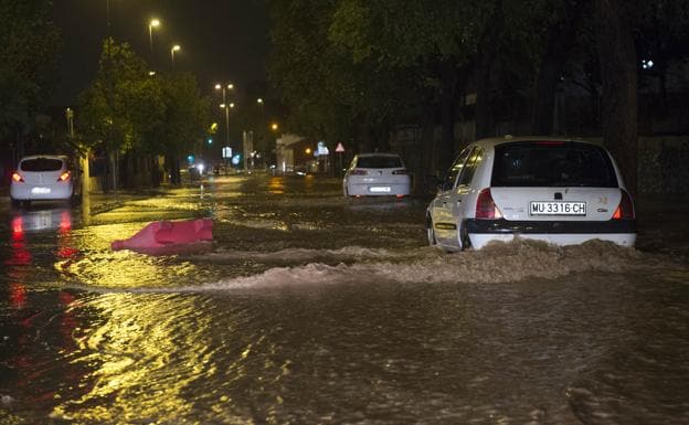 Vehículos circulan con dificultad por la calle Mariano Rojas de Murcia anegada por el agua. 