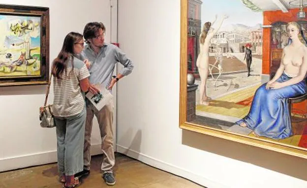 Dos visitantes de la muestra 'Destacados' observan con detenimiento una de las obras expuestas en el Palacio Almudí.
