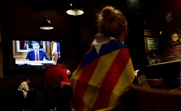Una mujer con una estelada sigue el discurso del Rey en un bar de Barcelona.