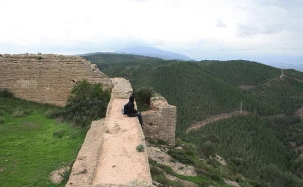 Un senderista descansa sobre una de las murallas del Castillo del Puerto (también llamado de La Asomada), que domina las laderas arboladas del Parque Regional El Valle-Carrascoy.