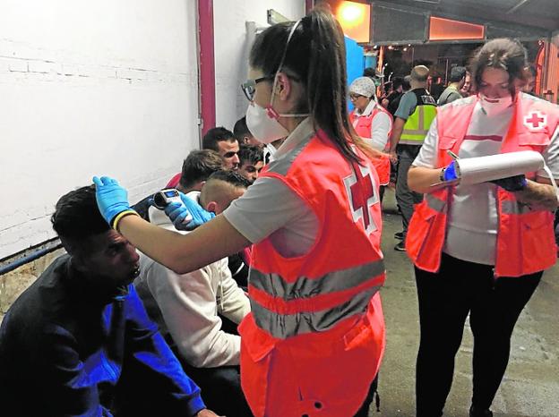 Voluntarios de Cruz Roja atienden a un grupo de inmigrantes, en la madrugada de ayer, a su llegada al puerto de Cartagena.