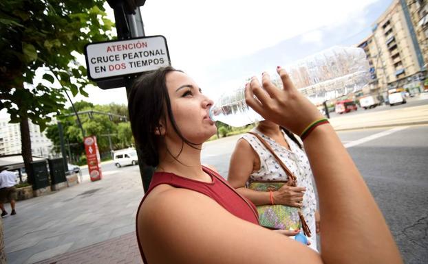 Una joven bebe agua en un día de intenso calor en Murcia. 