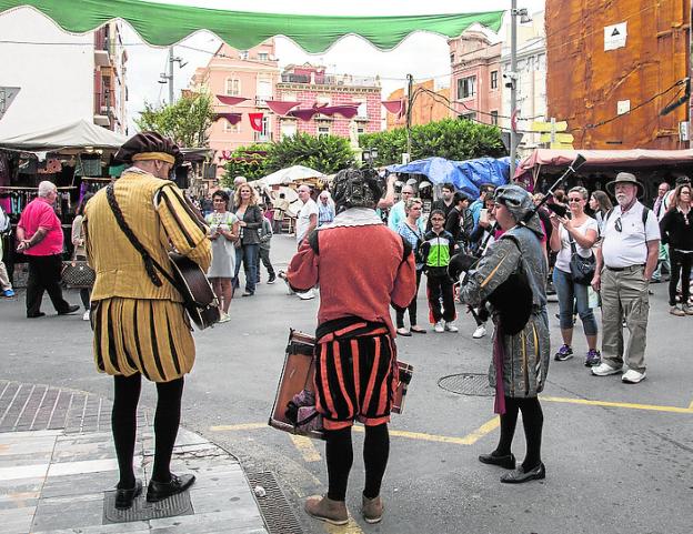 Unos turistas observan a unos músicos por el mercado.