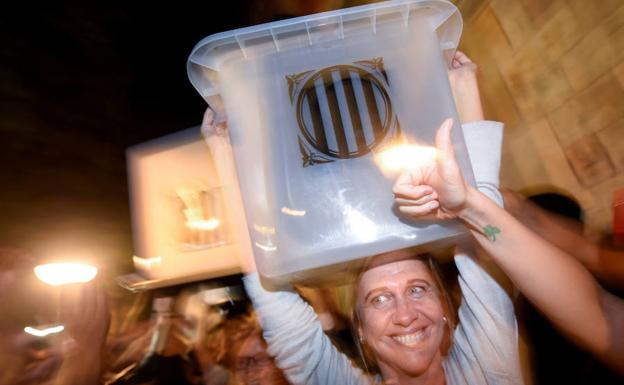 Una mujer lleva una de las urnas, en Barcelona. 