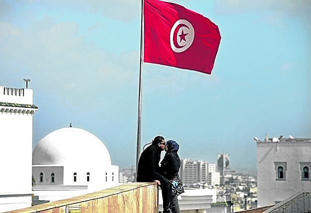 Una pareja se besa en una azotea, bajo la bandera de Túnez.