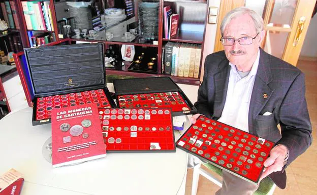 José María Conesa, en su casa, con sus monedas históricas y su libro.