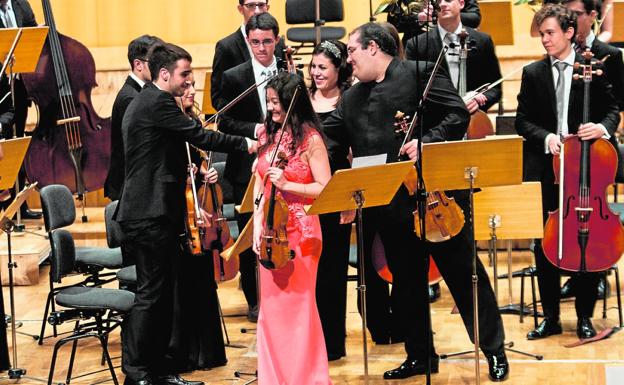 La violinista Lina Tur y el viola Joaquín Riquelme saludan a los músicos de la Orquesta de Jóvenes de la Región de Murcia y a su directora, Virginia Martínez, ayer, sobre el escenario del Auditorio regional Víctor Villegas.