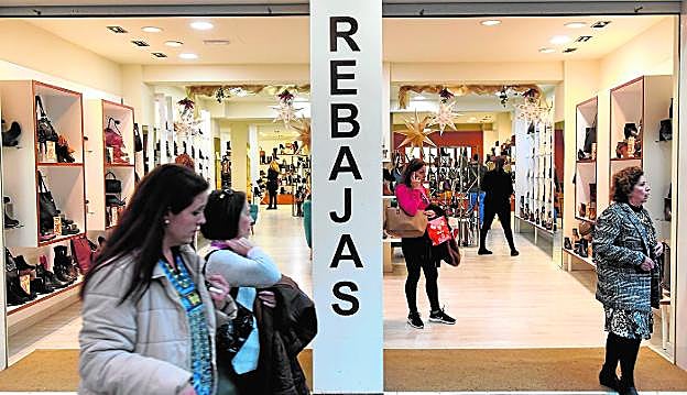 Clientes realizan sus compras, ayer, en una tienda de zapatos de Murcia que ya luce un cartel de la campaña de rebajas.