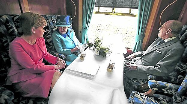 La reina Isabel, con su marido, el duque de Edimburgo, y la primera ministra escocesa, Nicola Sturgeon, el pasado martes en un tren.