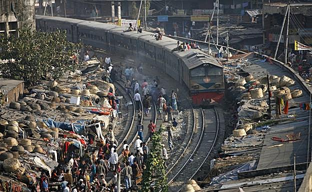 Un tren circula por la línea que cruza un improvisado asentamiento de chabolas, en Daca (Bangladés).