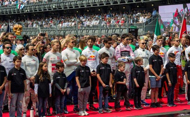 Un grupo de niños junto a los pilotos en un Gran Premio. 
